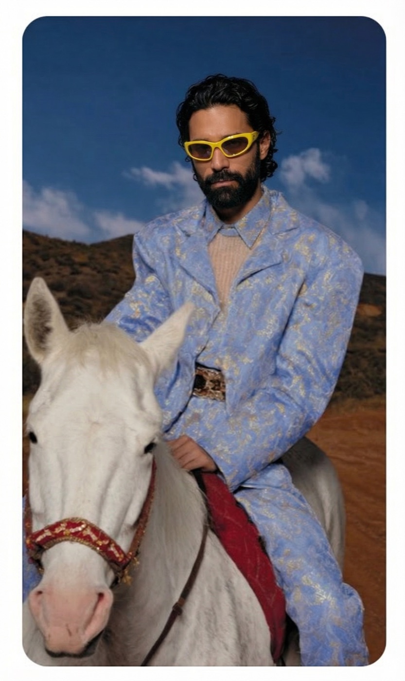 Amos Le Blanc on a white horse wearing a blue brocade suit and yellow sunglasses